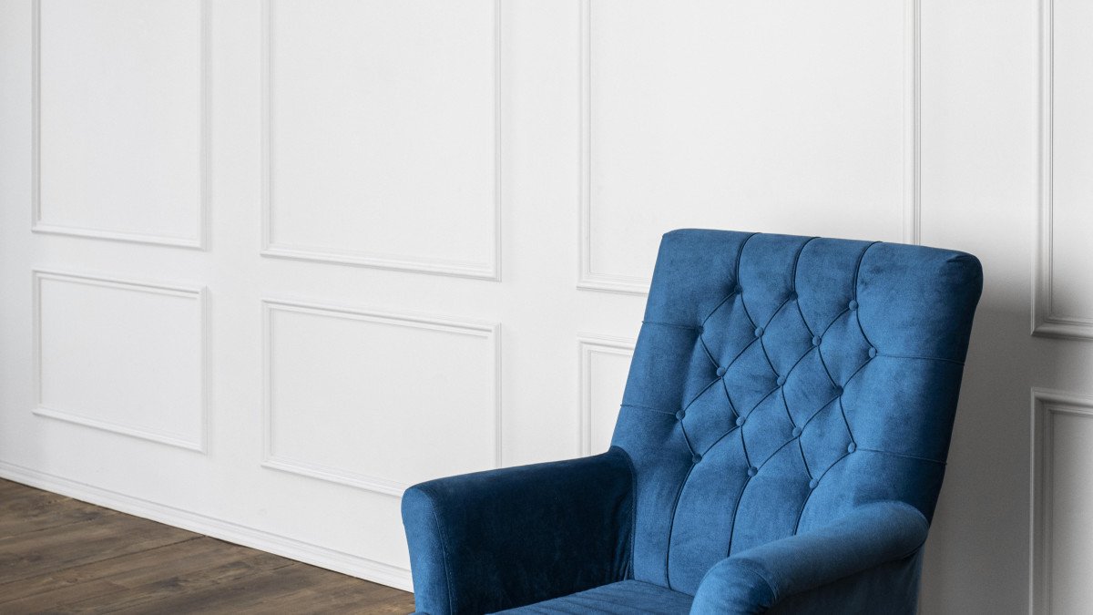un fauteuil bleu dans le coin d'une pièce blanche