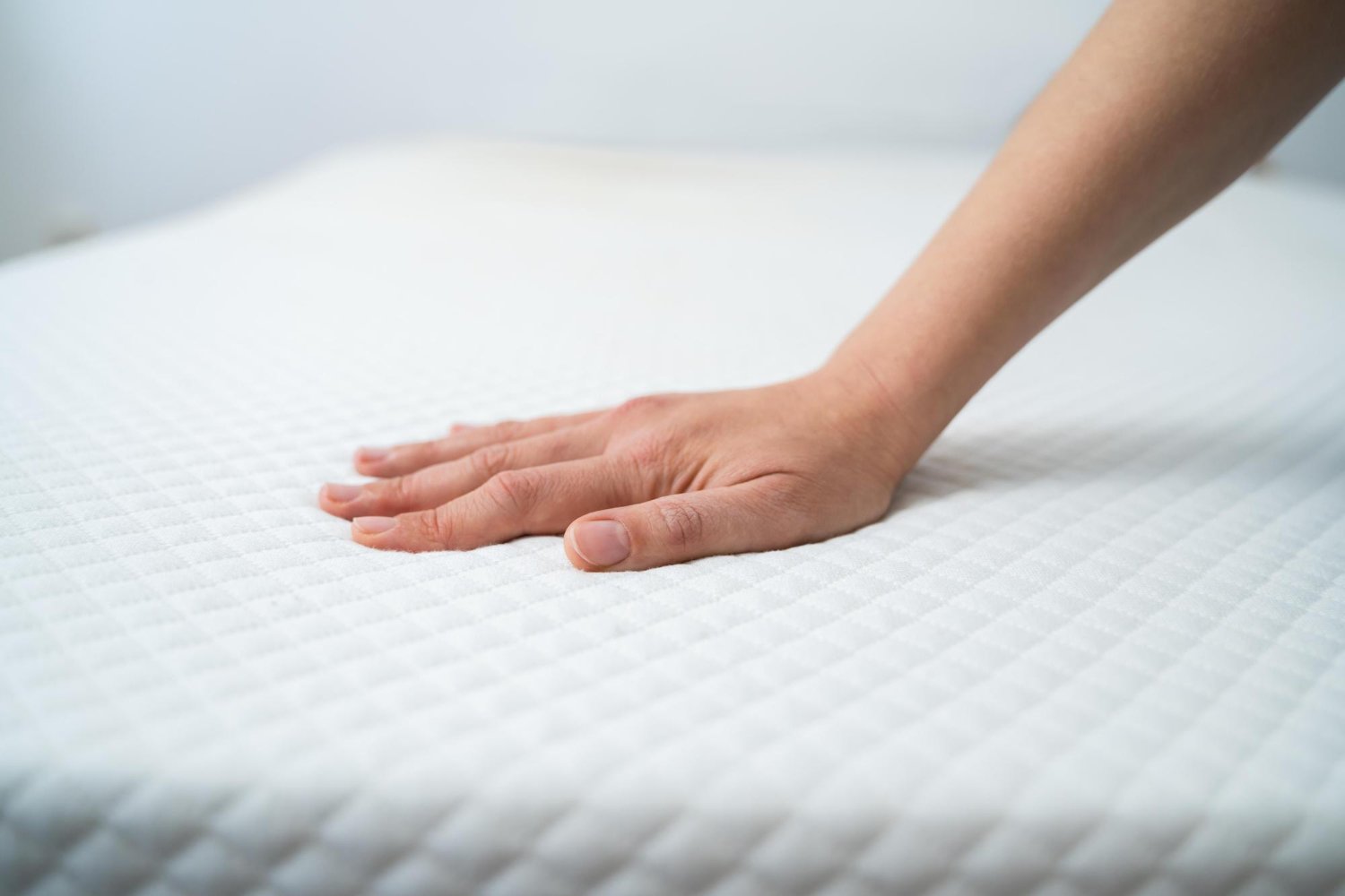 une main est posée sur un matelas afin d'en tester la fermeté